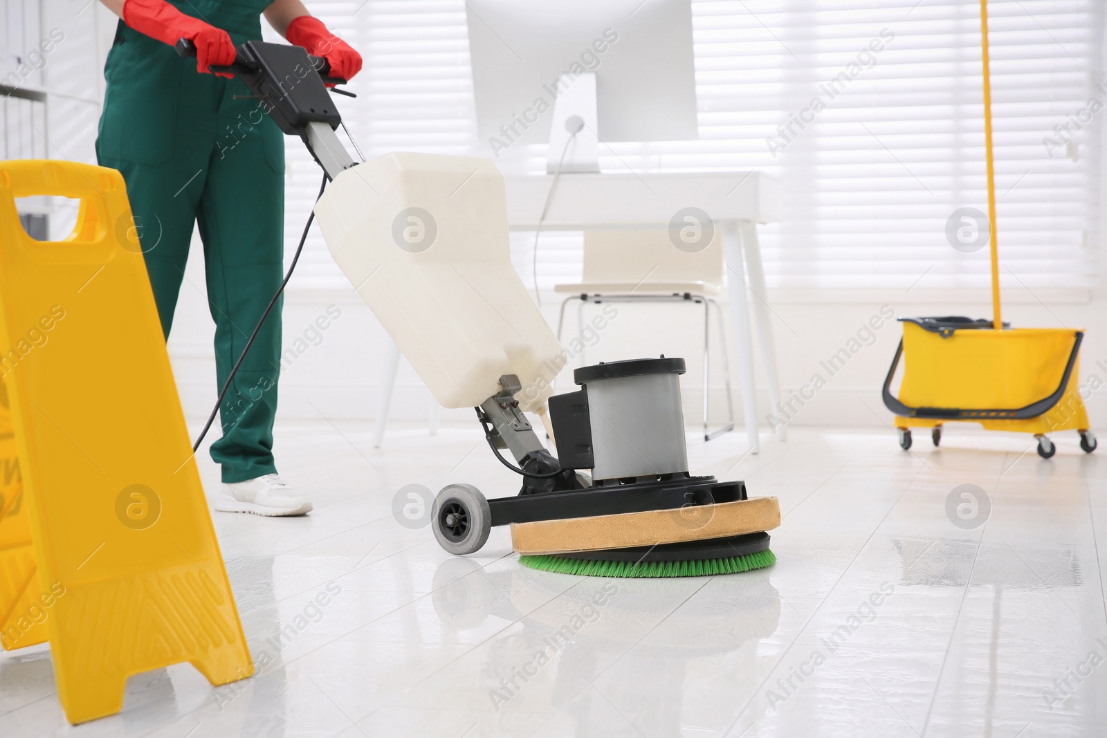 Photo of Professional janitor cleaning parquet floor with polishing machine in office, closeup