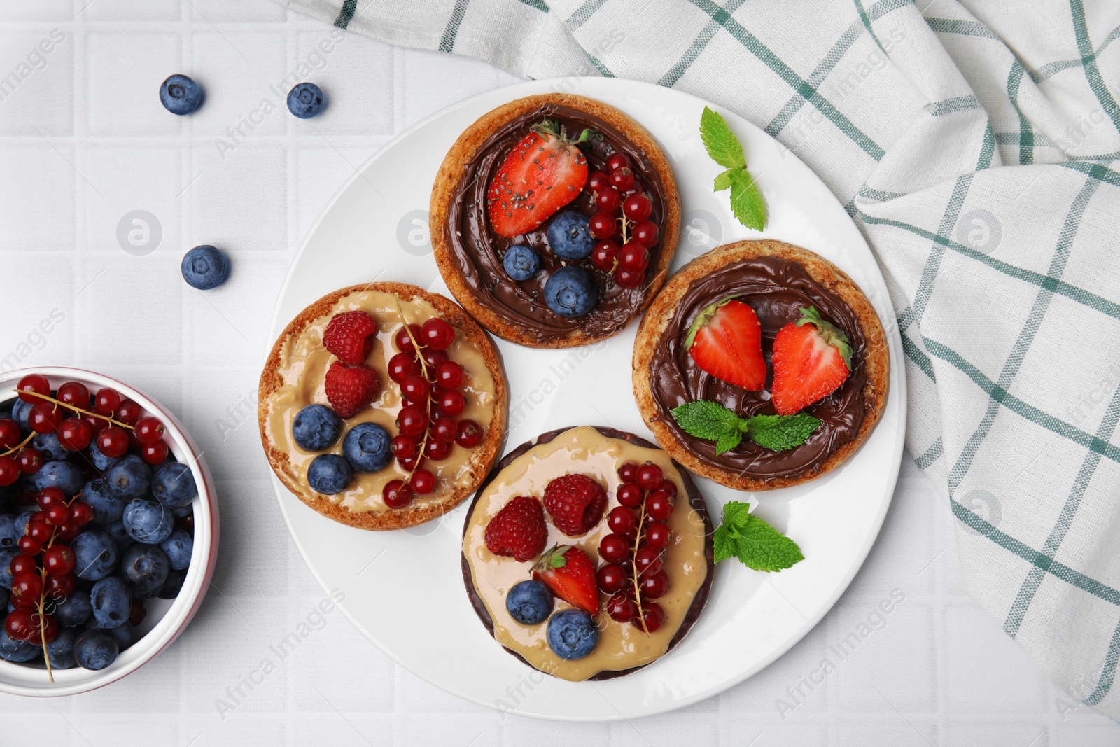 Photo of Fresh rice cake and rusks with different toppings served on white table, flat lay