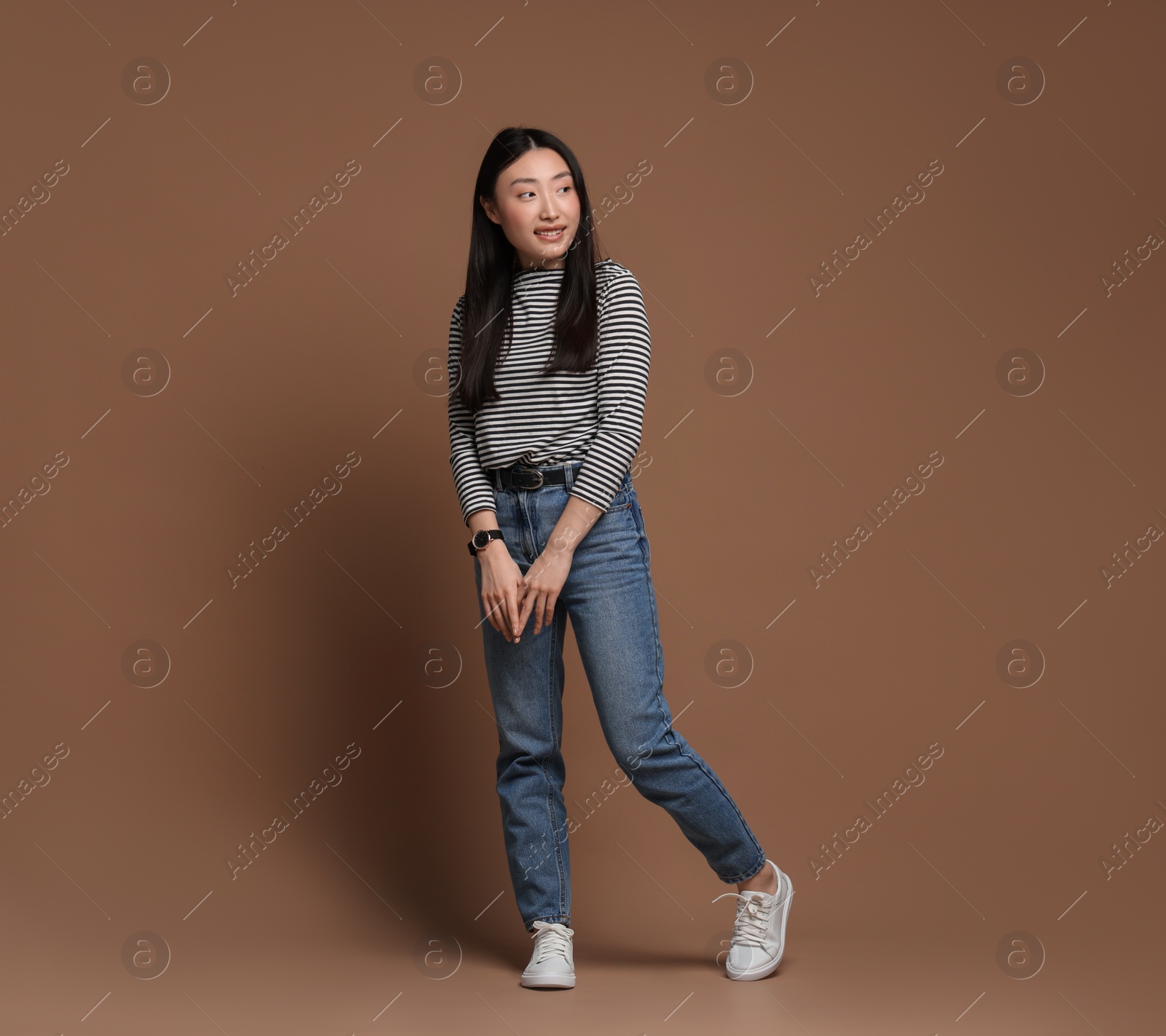 Photo of Full length portrait of smiling woman on brown background. Space for text