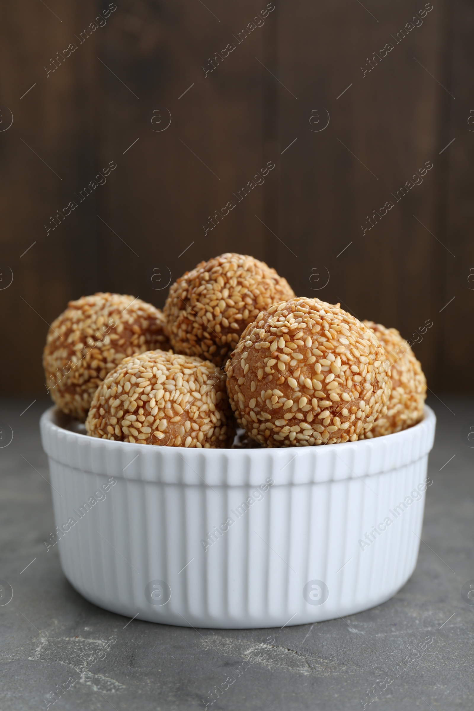 Photo of Bowl of delicious sesame balls on grey table