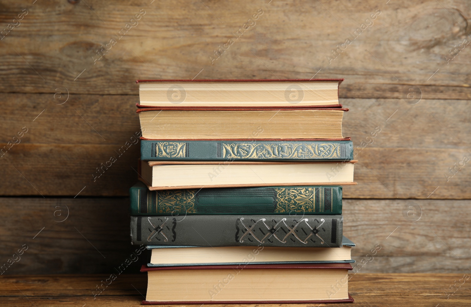 Photo of Collection of different books on table against wooden background