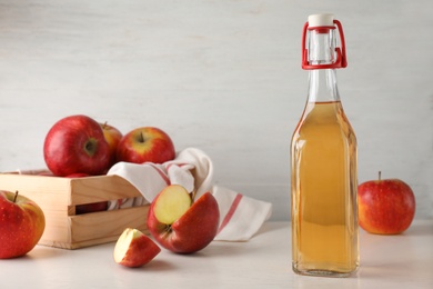 Photo of Composition with bottle of apple vinegar on table. Space for text