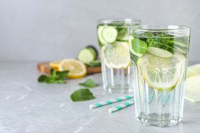 Photo of Refreshing water with cucumber, lemon and mint on light grey table. Space for text