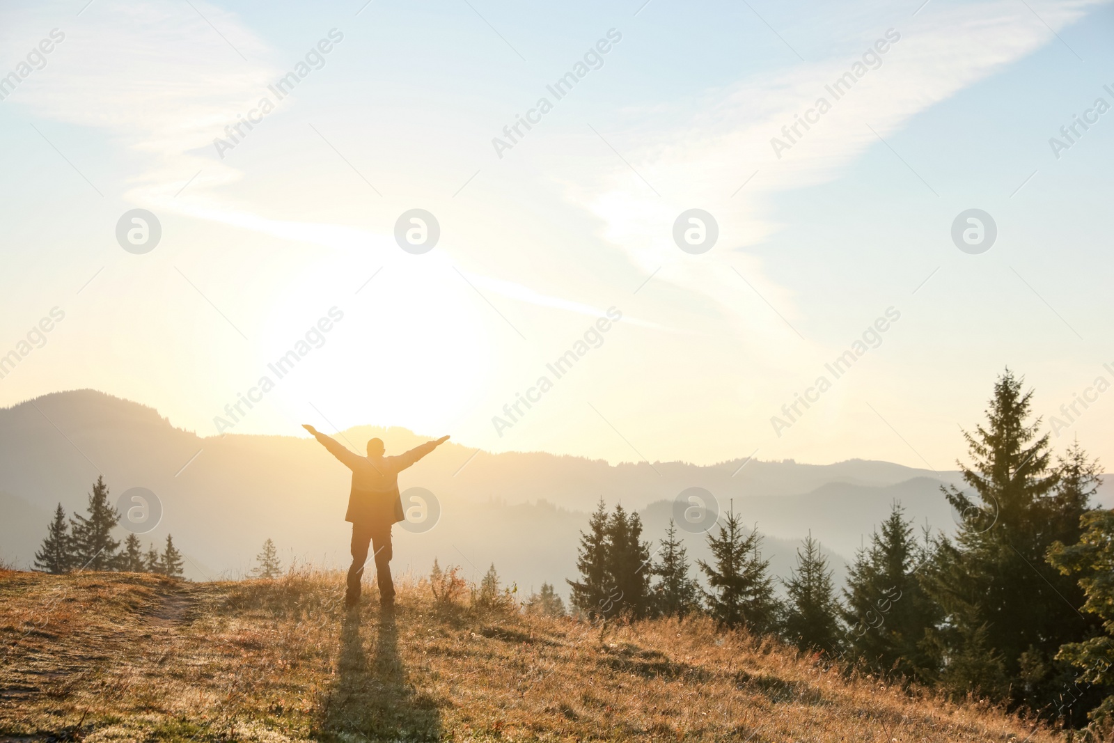 Photo of Man enjoying sunrise in mountains, back view. Space for text