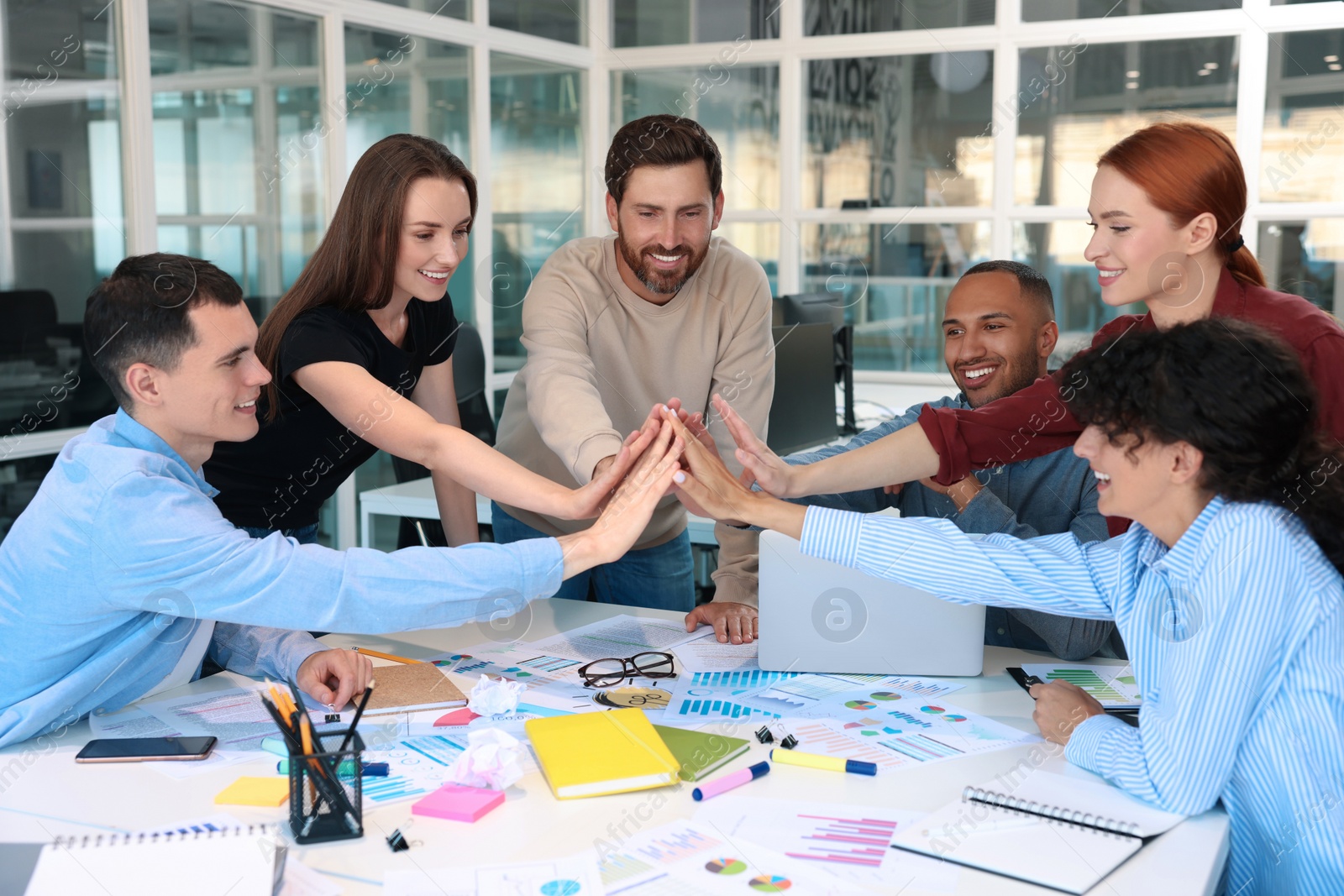 Photo of Team of employees joining hands in office. Startup project