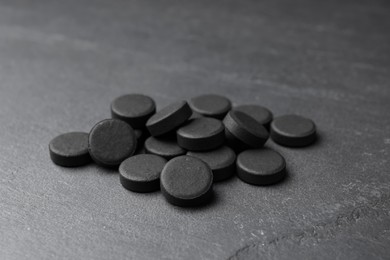 Photo of Pile of activated charcoal pills on black table. Potent sorbent