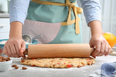 Photo of Woman rolling dough for Stollen at grey table, closeup. Baking traditional German Christmas bread