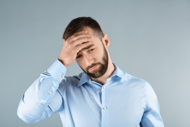 Photo of Young man suffering from headache on light background