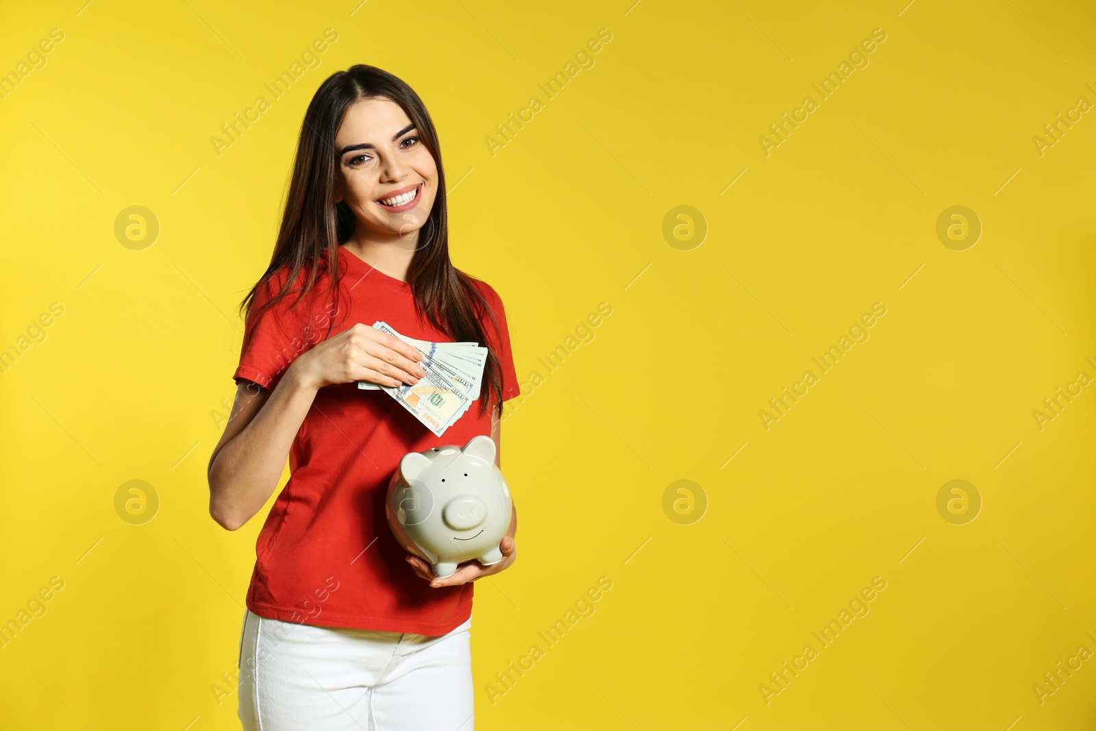Photo of Young woman with piggy bank and money on color background. Space for text
