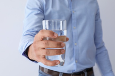 Photo of Man holding glass of pure water on white background, closeup