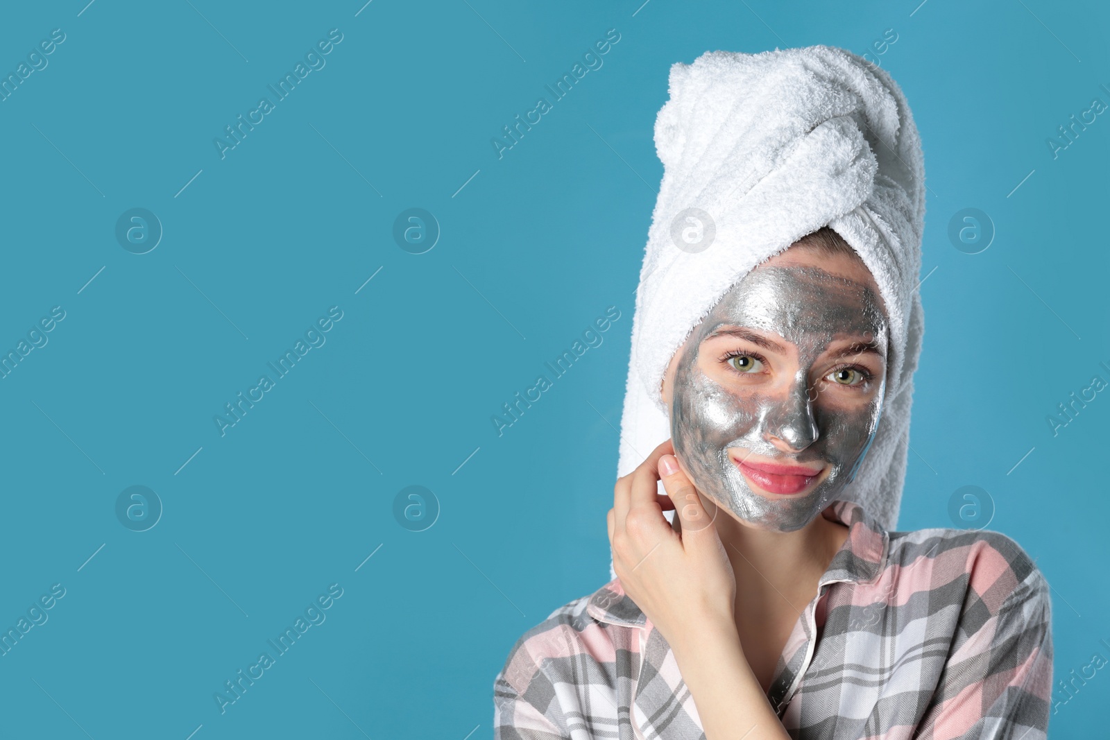 Photo of Young woman with cleansing mask on her face against color background, space for text. Skin care