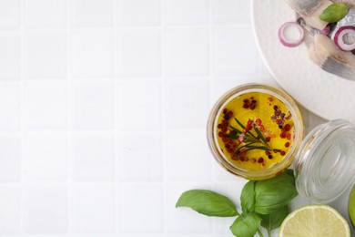 Photo of Tasty fish marinade in jar and products on light tiled table, flat lay. Space for text