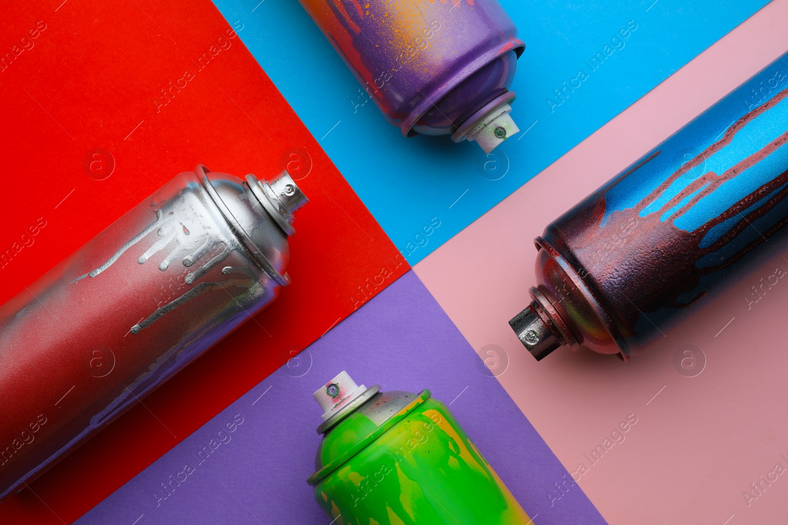 Photo of Used cans of spray paints on color background, flat lay. Graffiti supplies