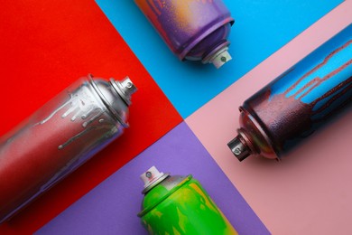 Photo of Used cans of spray paints on color background, flat lay. Graffiti supplies