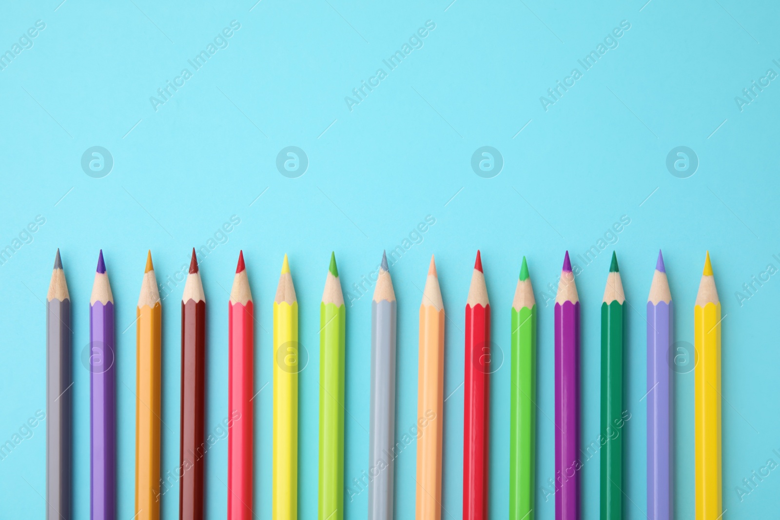 Photo of Colorful wooden pencils on light blue background, flat lay. Space for text