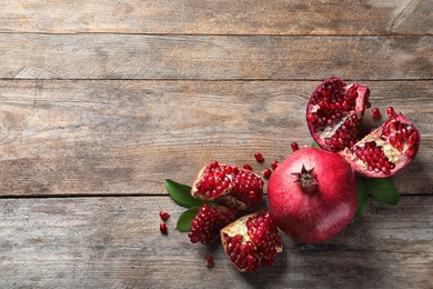 Photo of Composition with ripe pomegranates and space for text on wooden background, top view