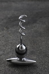 Photo of One metal corkscrew on grey textured table, closeup