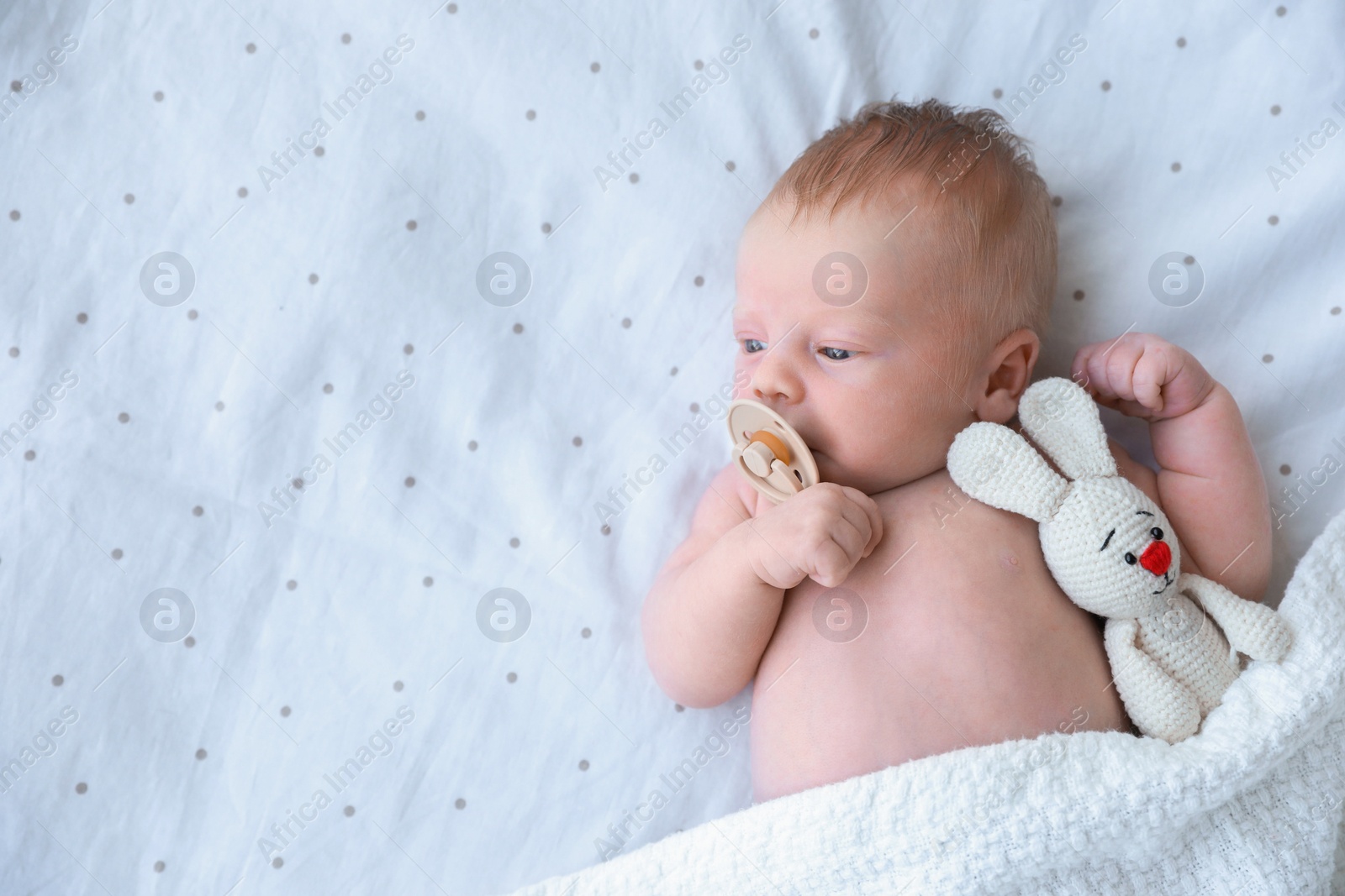Photo of Cute newborn baby with toy lying in bed, top view. Space for text