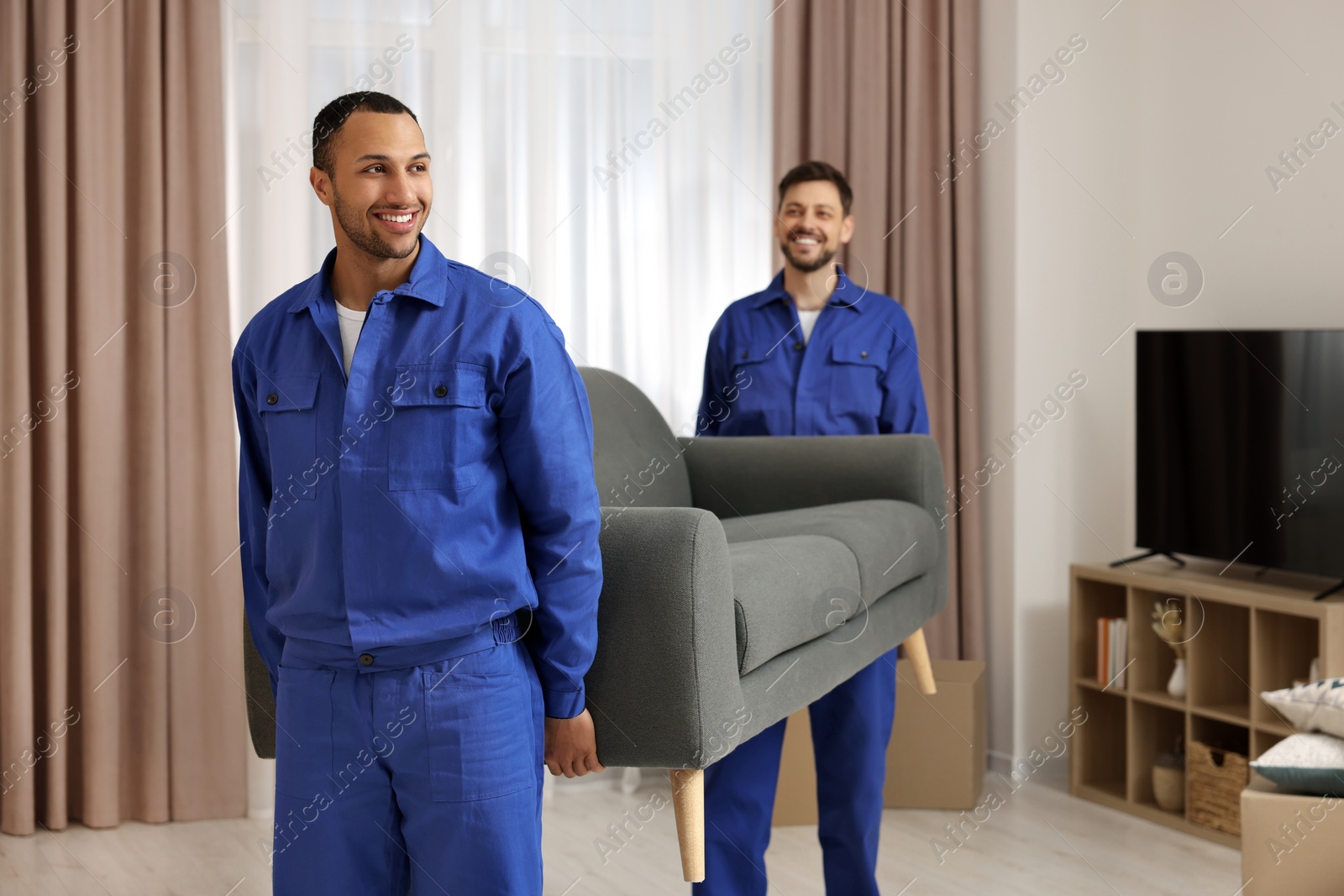 Photo of Male movers carrying sofa in new house