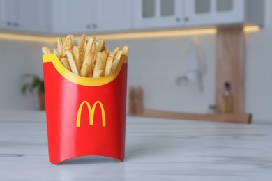 Photo of MYKOLAIV, UKRAINE - AUGUST 12, 2021: Big portion of McDonald's French fries on marble table in kitchen. Space for text