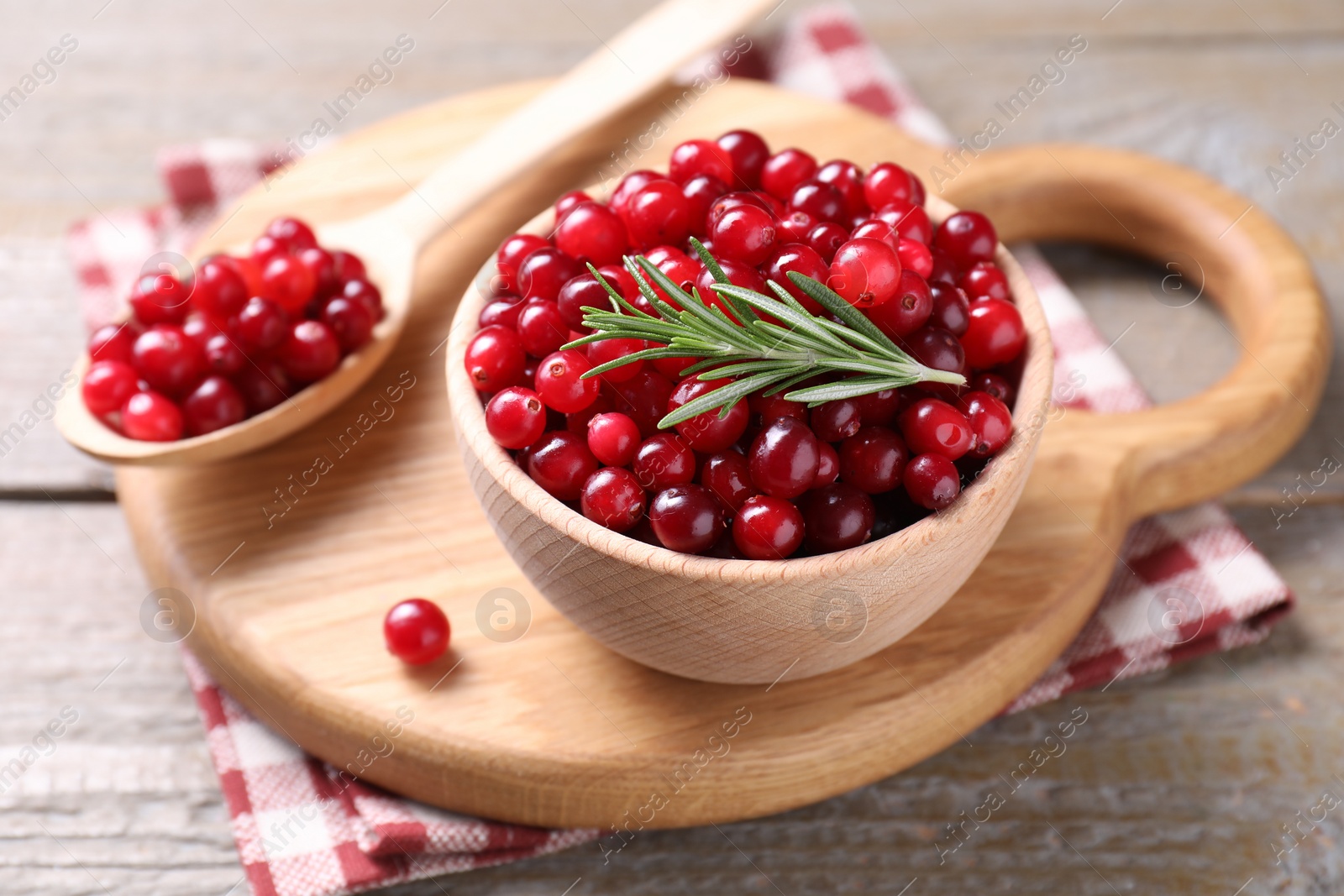 Photo of Fresh ripe cranberries and rosemary on wooden table