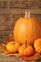 Pile of ripe pumpkins and dry leaves on wooden table