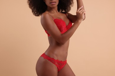 Photo of Woman in elegant red underwear on beige background, closeup