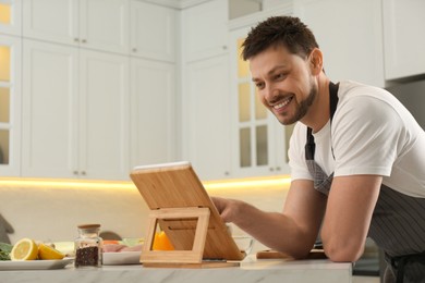 Man watching online cooking course via tablet in kitchen