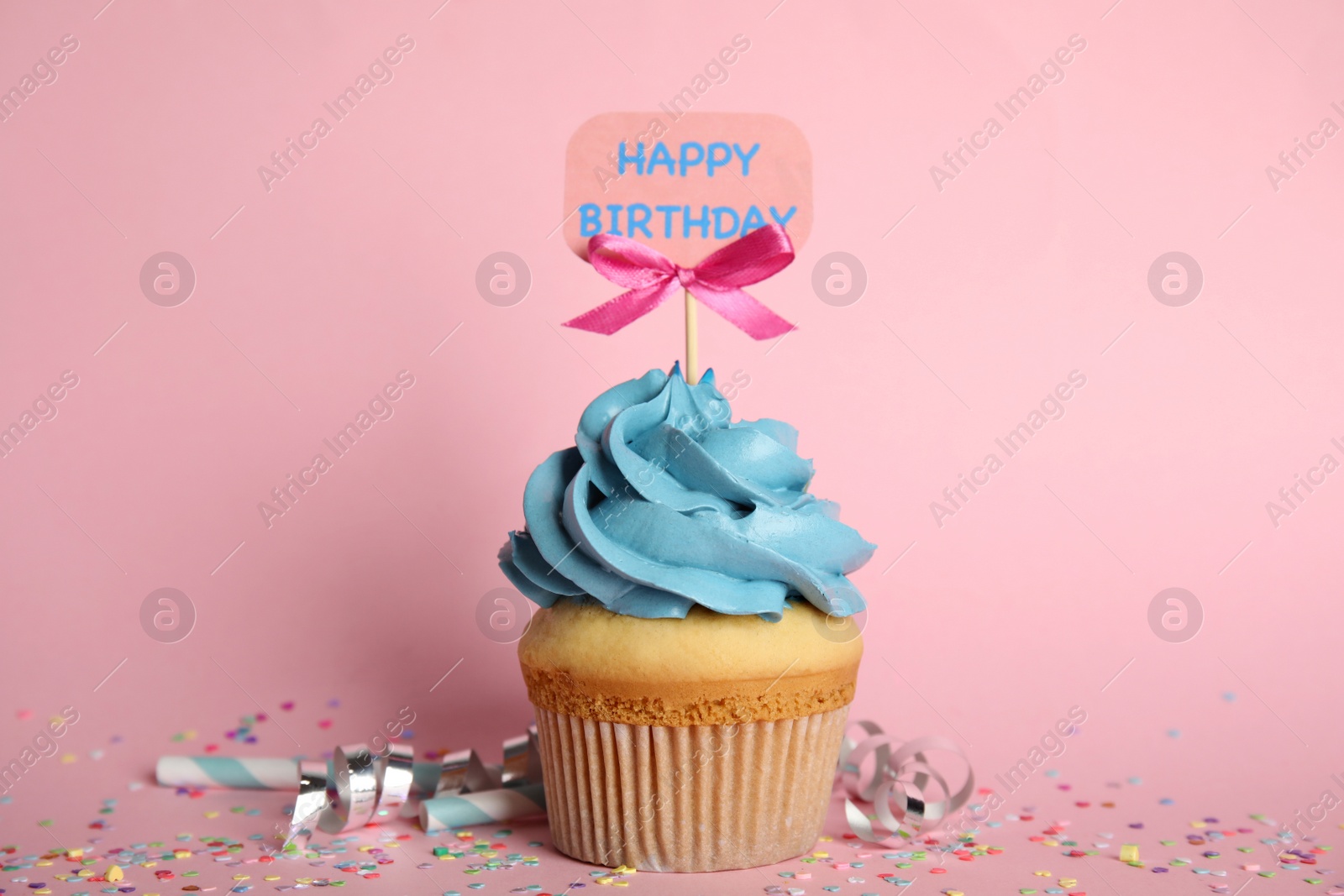 Photo of Beautiful birthday cupcake, streamers and confetti on pink background