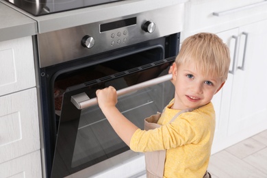 Little boy baking something in oven at home