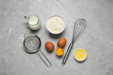 Photo of Ingredients for crepes, whisk and sieve on light grey table, flat lay