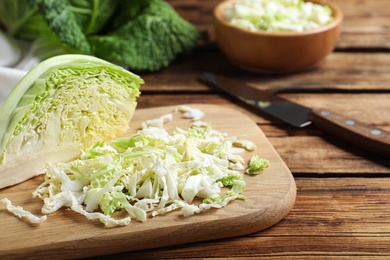 Photo of Cut fresh savoy cabbage on wooden table, closeup