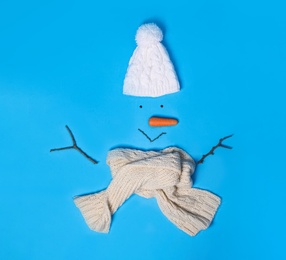 Photo of Creative snowman shape made of different items on light blue background, flat lay