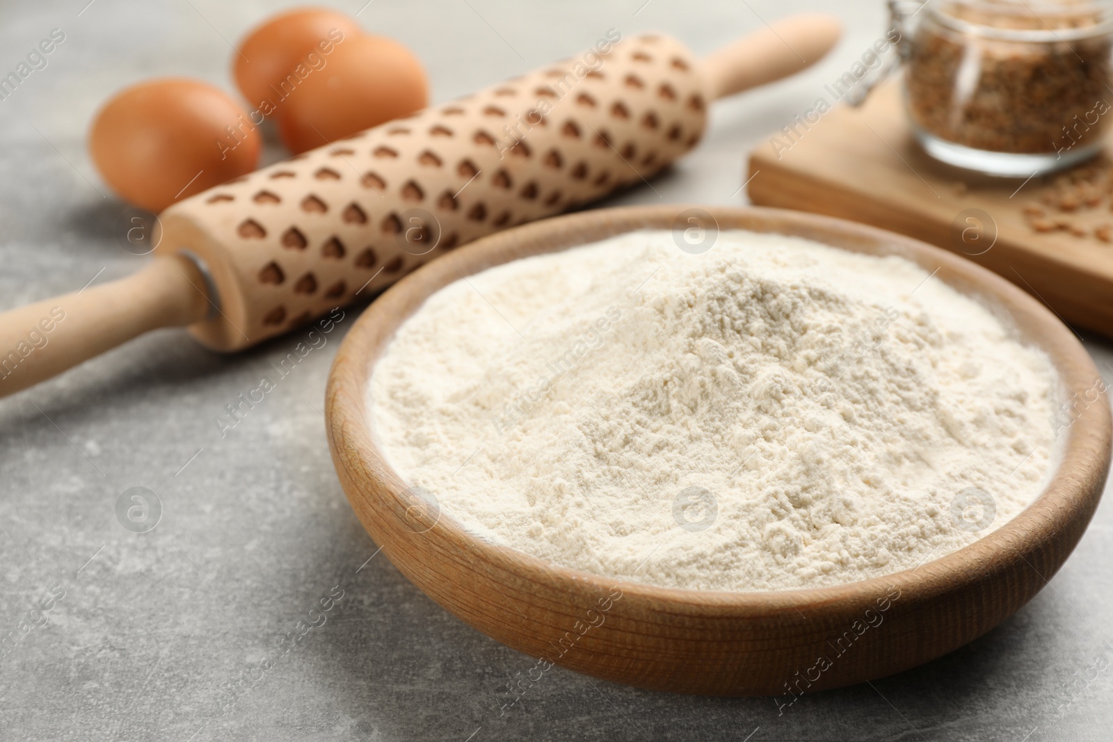 Photo of Wooden plate with flour on light grey table, closeup