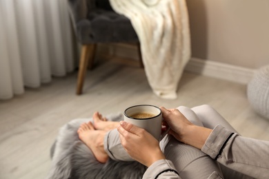 Photo of Woman with cup of hot drink resting at home, closeup