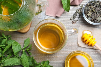 Flat lay composition with cup of hot aromatic mint tea on wooden table