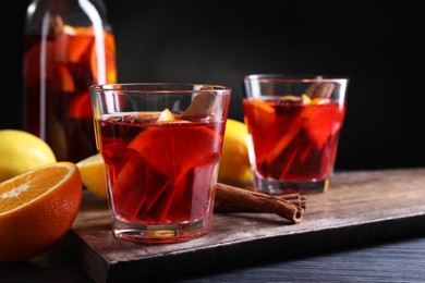 Photo of Aromatic punch drink and ingredients on black table. Space for text