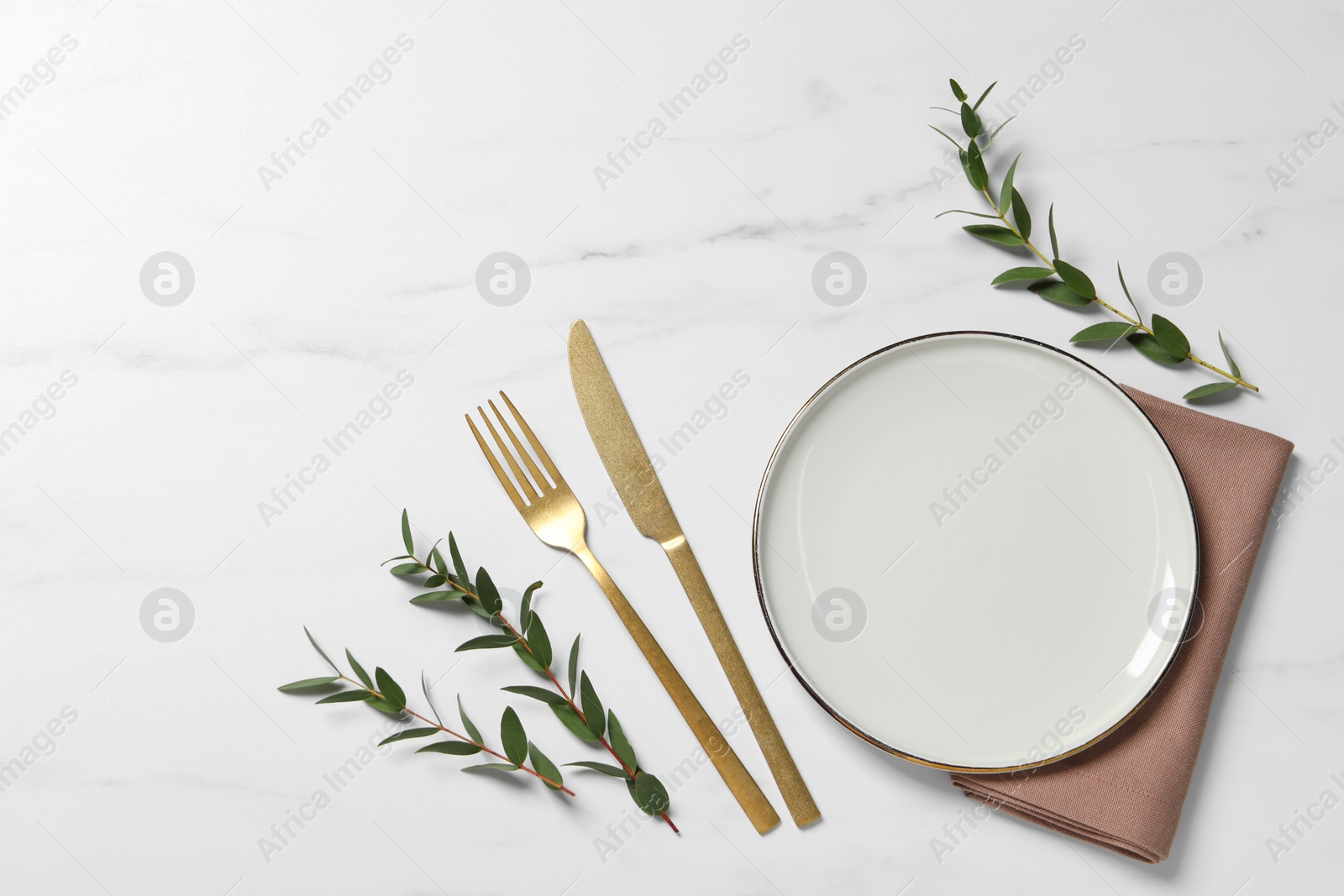 Photo of Stylish setting with cutlery and eucalyptus leaves on white marble table, flat lay. Space for text