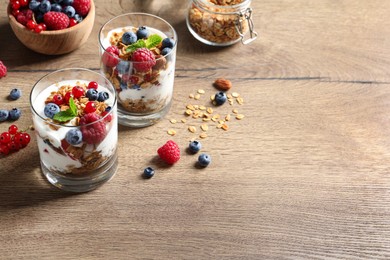Image of Tasty dessert with yogurt, berries and granola on wooden table. Space for text 