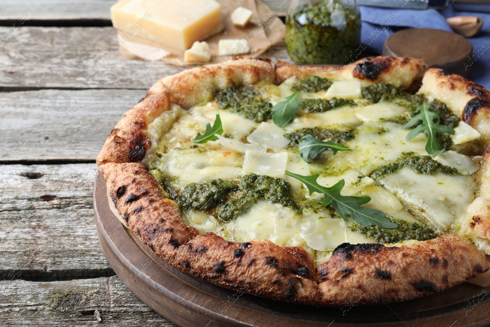 Photo of Delicious pizza with pesto, cheese and arugula on wooden table, closeup