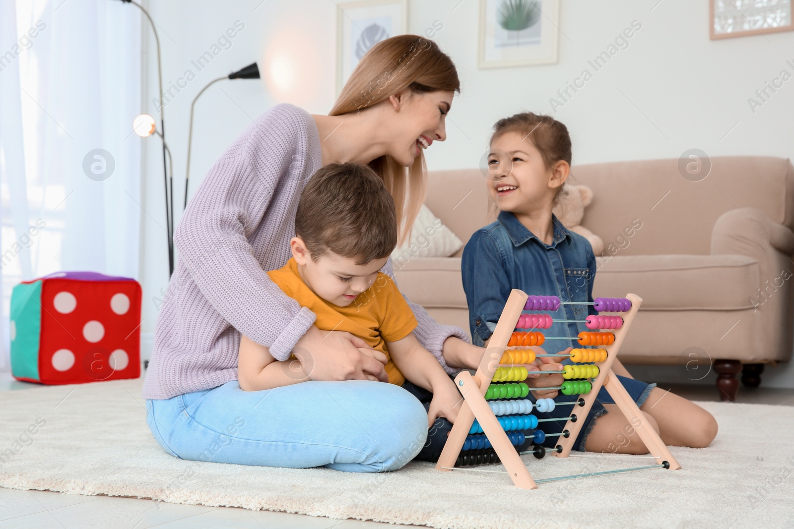 Photo of Nanny and little children playing with counting frame at home