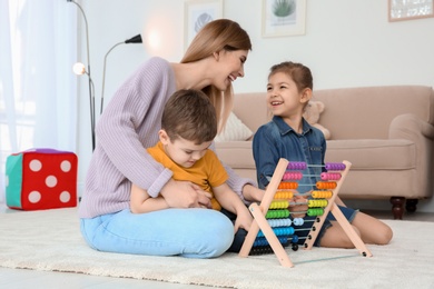 Photo of Nanny and little children playing with counting frame at home