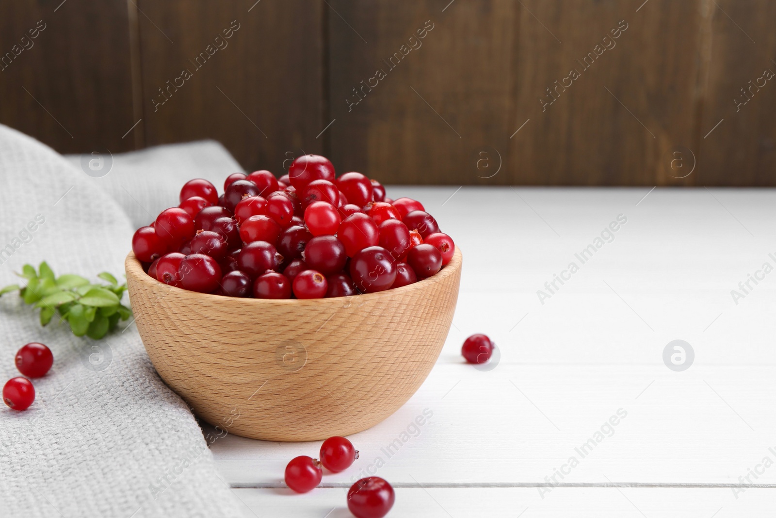 Photo of Fresh ripe cranberries on white wooden table, space for text