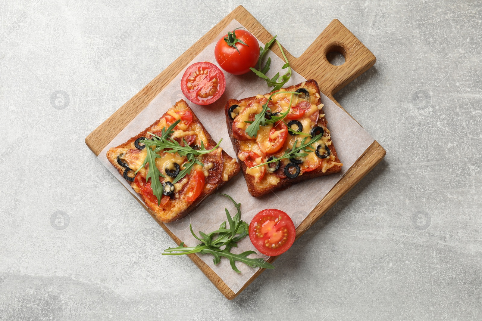 Photo of Tasty pizza toasts, fresh tomatoes and parsley on grey table, top view