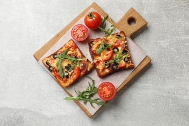 Photo of Tasty pizza toasts, fresh tomatoes and parsley on grey table, top view