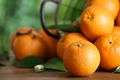 Photo of Fresh ripe oranges on wooden table against blurred background. Space for text