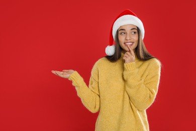 Photo of Happy woman in Santa hat on red background, space for text. Christmas countdown