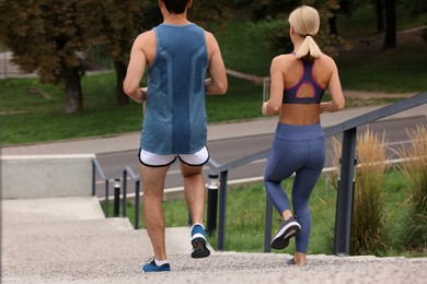 Photo of Healthy lifestyle. Couple running down stairs outdoors, back view