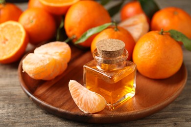 Photo of Bottle of tangerine essential oil and fresh fruits on wooden table