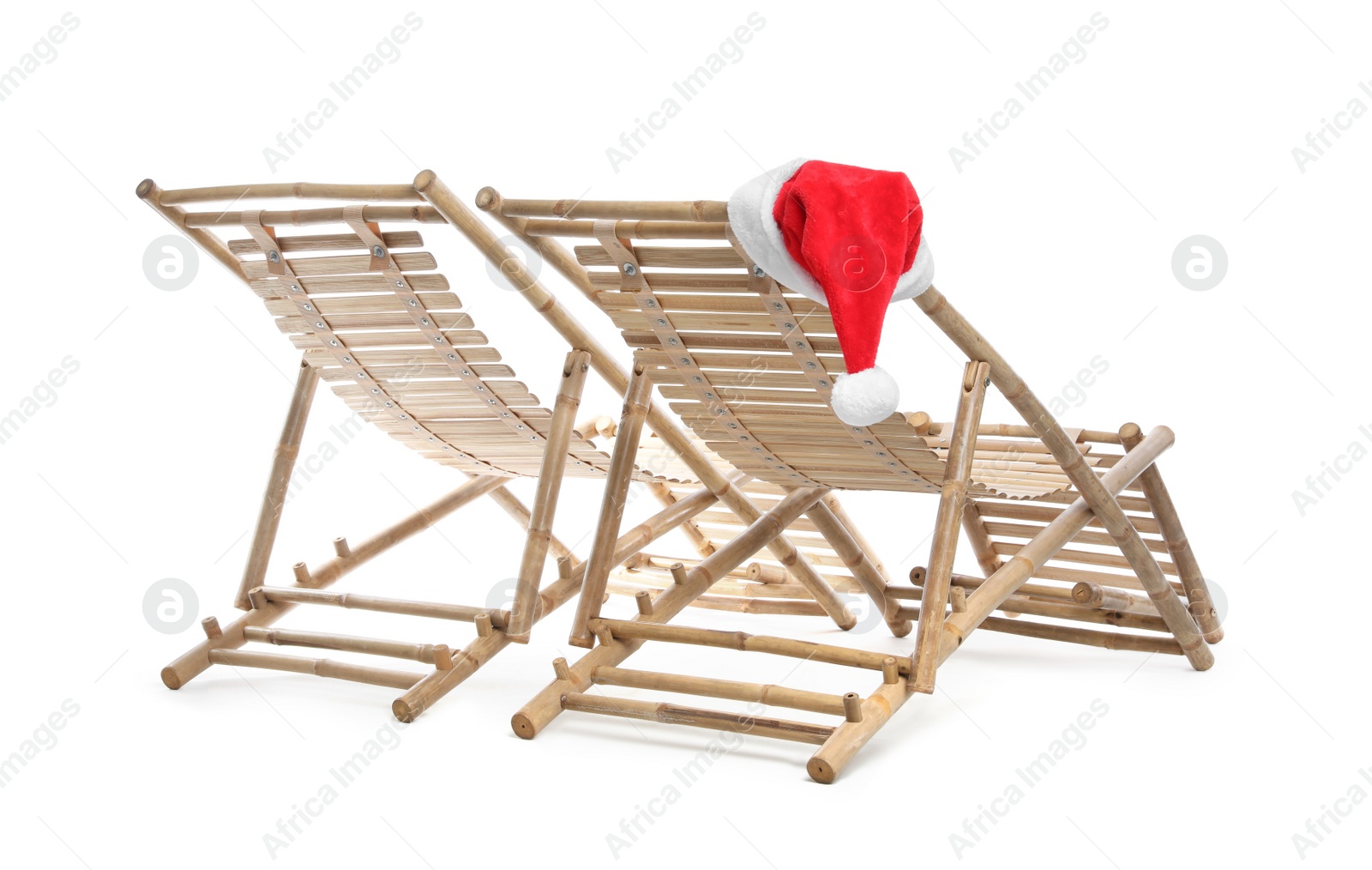 Photo of Wooden deck chairs and Santa Claus hat on white background. Christmas vacation